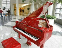 a red piano sitting in the middle of a lobby