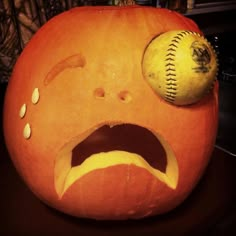 an orange pumpkin with a baseball on it's face