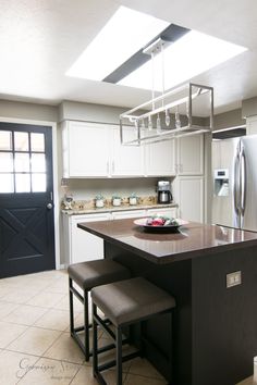 a kitchen with white cabinets and marble counter tops, black chairs in front of the island