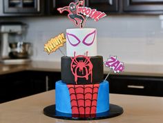 a three tiered cake with spiderman decorations on it's top and bottom