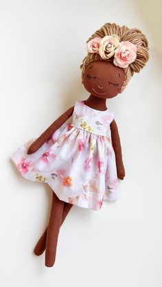 a brown doll wearing a white dress with pink flowers on it's head and hair