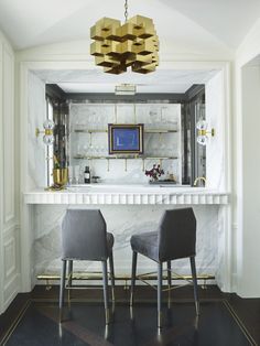 two chairs sitting at a bar in a room with marble counter tops and gold fixtures