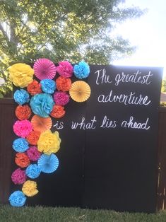 a sign that says the greatest adventure is what lies ahead with paper flowers on it