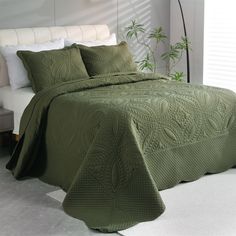 a bed with a green bedspread and pillows