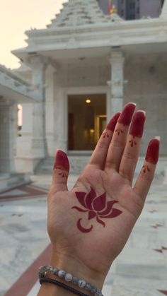 a woman's hand with red paint on it and a flower painted on the palm