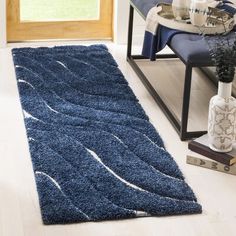 a blue area rug on the floor in front of a chair and table with vases