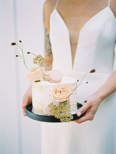 a woman holding a cake with flowers on it