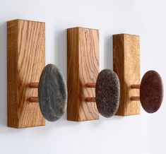 three rocks are mounted to the side of a wooden wall hanging on a white wall