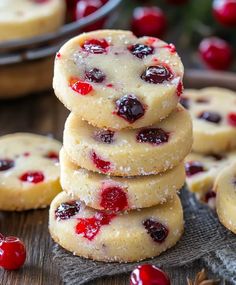 cranberry shortbread cookies stacked on top of each other with fresh cherries in the background