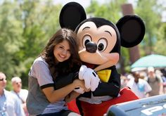 a woman is hugging a mickey mouse mascot