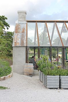 people are sitting in the back of a building with plants growing out of it's windows