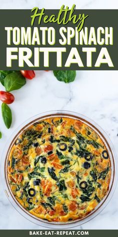 an egg dish with spinach and tomatoes in it on top of a marble counter