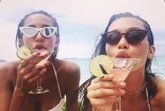 two beautiful young women drinking cocktails at the beach