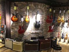 guitars and amps are hanging up on the wall in a music store or studio