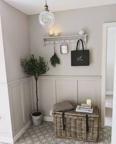 a room with a basket, potted plant and two candles on the wall next to it