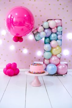 a birthday cake and balloons are on the floor in front of a number one sign