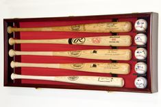 six baseball bats in a wooden case with balls on the bottom and one ball inside