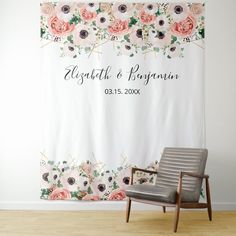 a chair sitting in front of a floral wall hanging