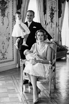 an old black and white photo of two people sitting in chairs with a baby on their lap