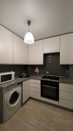 an empty kitchen with white cabinets and black counter tops, including a washer and dryer