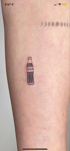 a small tattoo on the leg of a woman's thigh with a soda bottle in it