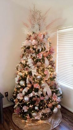 a decorated christmas tree in the corner of a room with wood floors and white walls