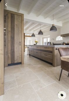 an open kitchen and dining area with wooden cabinets, marble flooring and pendant lights