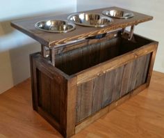 a wooden table with three bowls on top and two spoons in the bottom drawer