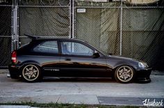 a black car parked in front of a fence