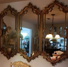 three mirrors are hanging on the wall above a dresser and mirror in a living room