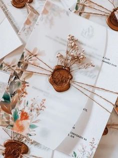 some brown buttons are sitting on top of white envelopes with flowers and leaves in them