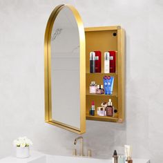 a bathroom sink with a gold medicine cabinet in the middle and various items on it