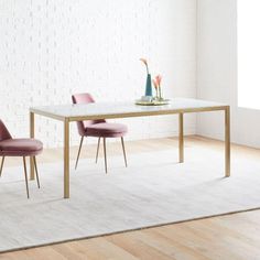 a table with two chairs and a vase on top of it in front of a white brick wall