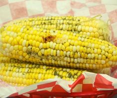 two corn cobs sitting on top of a red basket