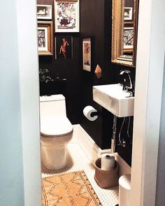 a white toilet sitting next to a sink in a bathroom under pictures on the wall