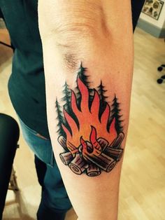 a man with a tattoo on his arm that has a fire and logs in it