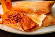 two tamales on a plate with meat and sauce