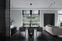 a modern living room with black and white furniture, large windows, and dark wood flooring