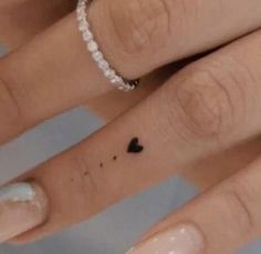 two people with wedding rings on their fingers, one has a small heart tattooed on the middle finger