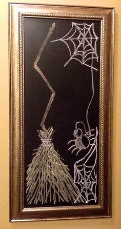 a chalkboard drawing of a broom and spiderweave on a black board in a gold frame