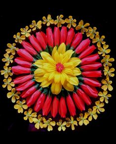 an overhead view of red and yellow flowers in the center of a circular arrangement on a black background