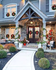 a house decorated for christmas with wreaths on the front door and entry way to it