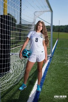 a female soccer player posing for a photo in front of the goalie's net