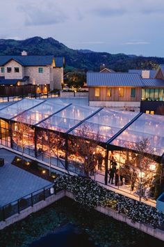 an aerial view of a glass building with people standing outside at night in the evening