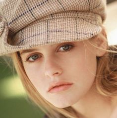 a young woman wearing a hat and looking at the camera with an intense look on her face