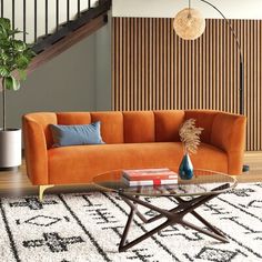 an orange couch sitting on top of a rug next to a coffee table and stairs