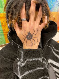 a person with a spider tattoo on their hand and headphones in front of them