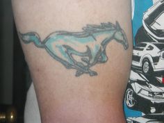 a tattoo on the arm of a man with a horse and car in the background