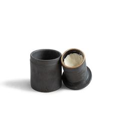 two black cups sitting next to each other on a white surface