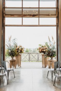 two chairs are set up in front of an open door with floral arrangements on them